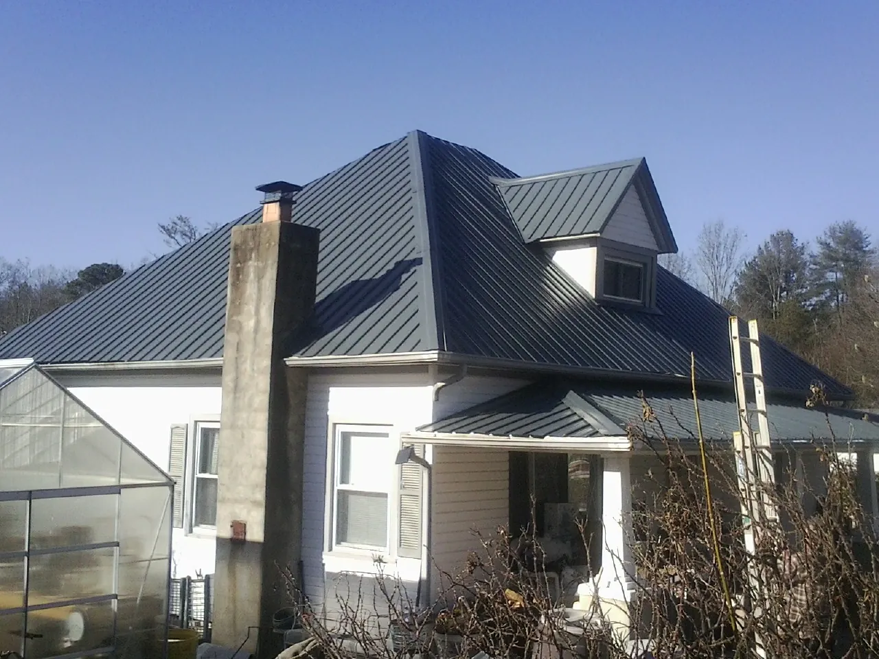 Dark blue standing seam metal roof on a white farmhouse with dormer — Slate & Tile Roof Repair by Roofing Brothers in Alsip