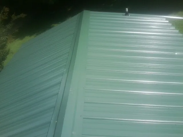 New green metal panels meeting at the ridge of a roof — Flat Roof Repair work by our crew in Alsip