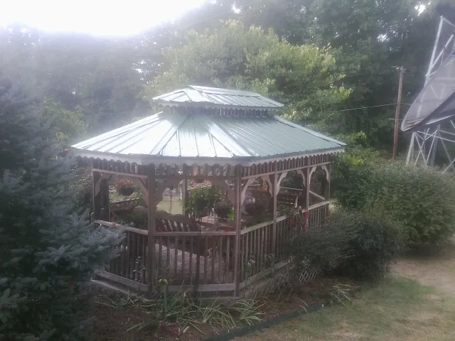 Green metal roof on a backyard gazebo surrounded by garden beds in Alsip