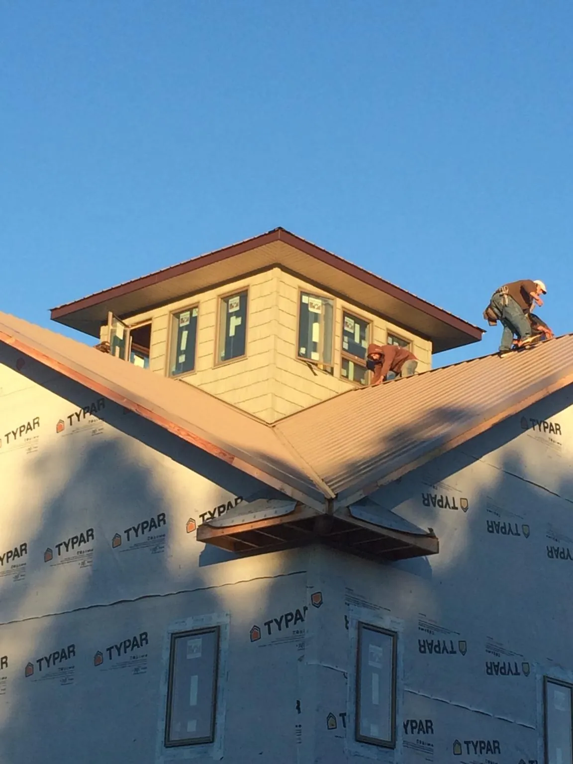 Roofers working around a rooftop cupola on a new metal roof at sunset — Roof Waterproofing in Alsip by Roofing Brothers
